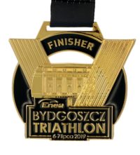 Medal odlewany enea bydgoszcz triathlon w złotym kolorze z elementami wypełnionymi czarną farbą