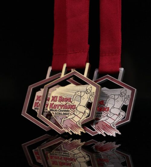 Nowoczesne medale na Bieg Katyński wycięte w geometryczny kształt z dynamicznym motywem biegacza
