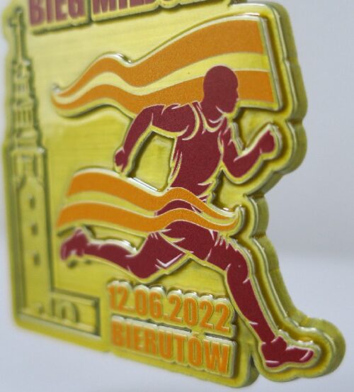 Medal na Bierutowski Bieg Miejski o ciekawym kształcie z trójwymiarowymi zdobieniami w postaci wieży ratusza oraz biegacza w ruchu - detal