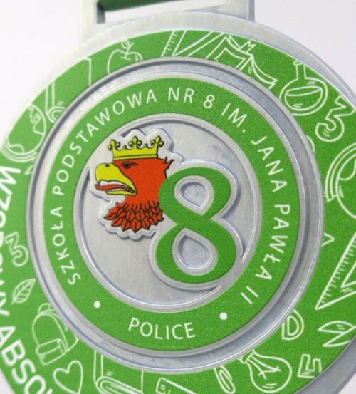 Medal Wzorowy Absolwent o owalnym kształcie z zielonym nadrukiem, logo szkoły oraz zdobieniami nawiązującymi do szkolnictwa - detal