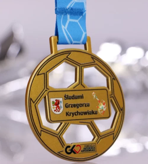 Medal na wydarzenie o nazwie ,,Śladami Grzegorza Krychowiaka" wykonany za pomocą cięcia laserowego przypomina kształtem piłkę