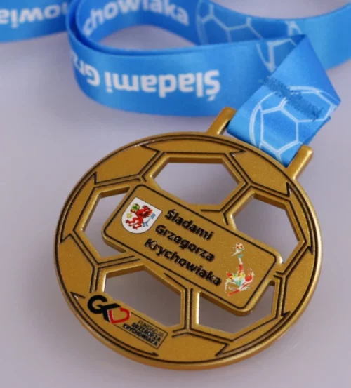 Medal na wydarzenie o nazwie ,,Śladami Grzegorza Krychowiaka" wykonany za pomocą cięcia laserowego przypomina kształtem piłkę - wstążka