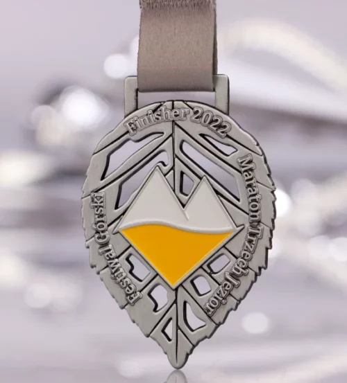 Medal na Maraton Trzech Jezior wykonany w kształcie liścia z kolorowym logo w centrum